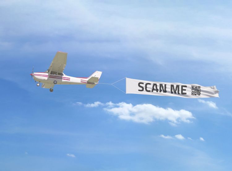 Flugzeug mit Werbebanner, auf dem ein QR-Code abgebildet ist.